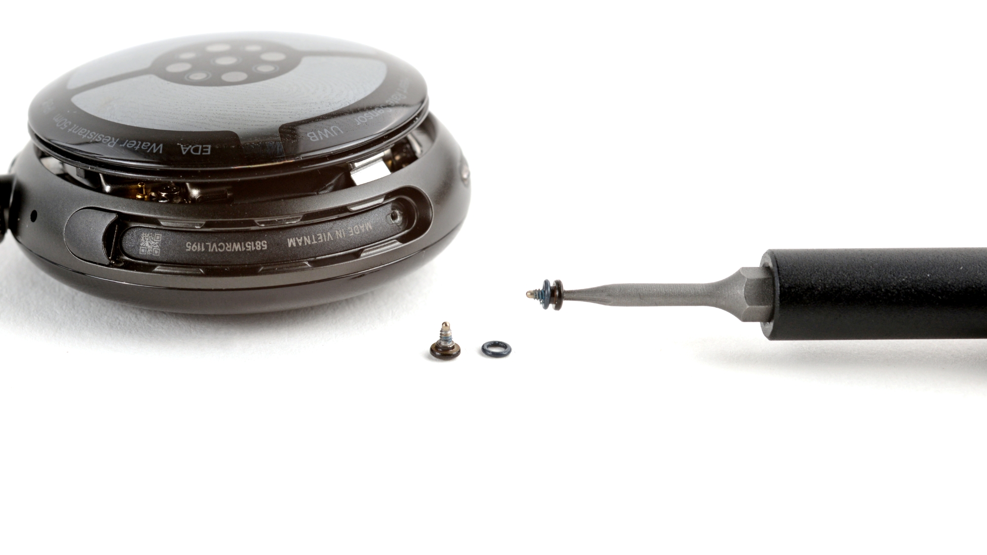 A hand using a Torx screwdriver bit to remove a screw from the Pixel Watch 4 chassis.