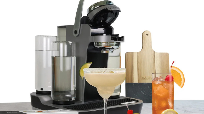 The Bartesian cocktail machine dispensing a drink into a glass on a home bar setup.