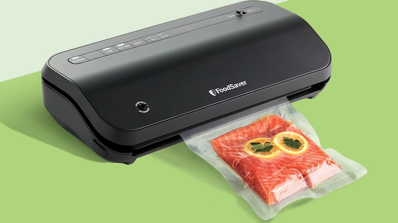 The FoodSaver system vacuum sealing a fresh salmon fillet in a clear plastic bag.