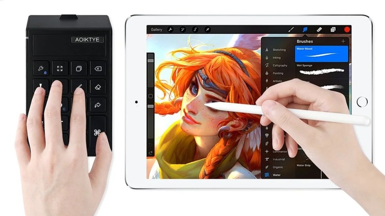 Close-up of an artist using a stylus on an iPad with a Procreate shortcut keyboard in their left hand.