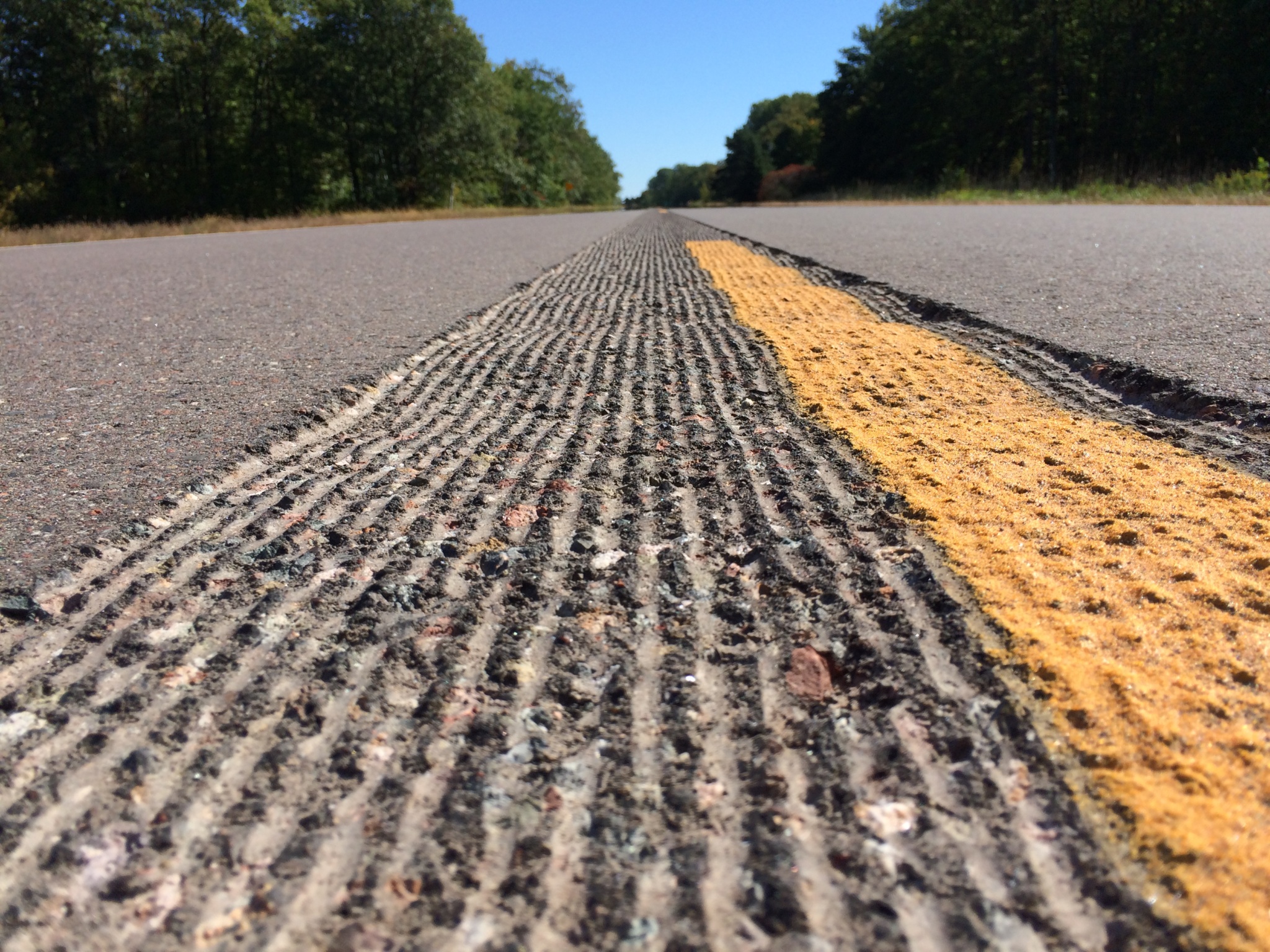 A wide-angle shot of a highway featuring sinusoidal mumble strips along the shoulder line.