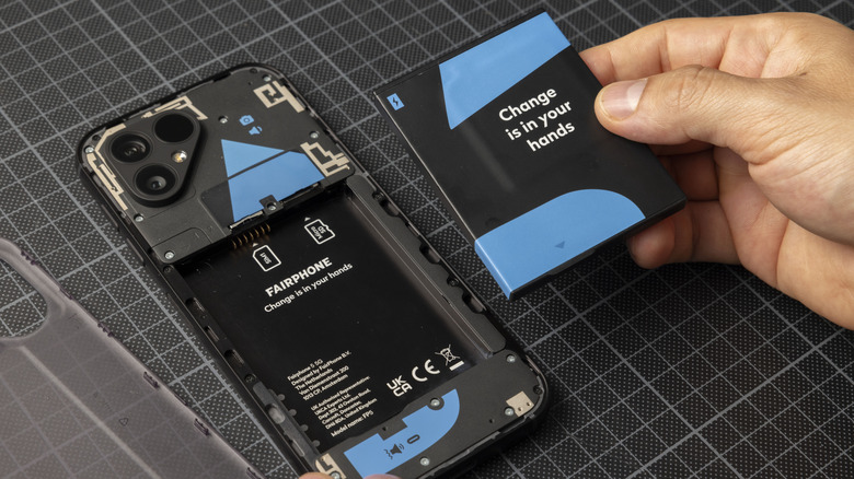 A modern Fairphone 5 with its back cover removed and a swappable battery held next to it.