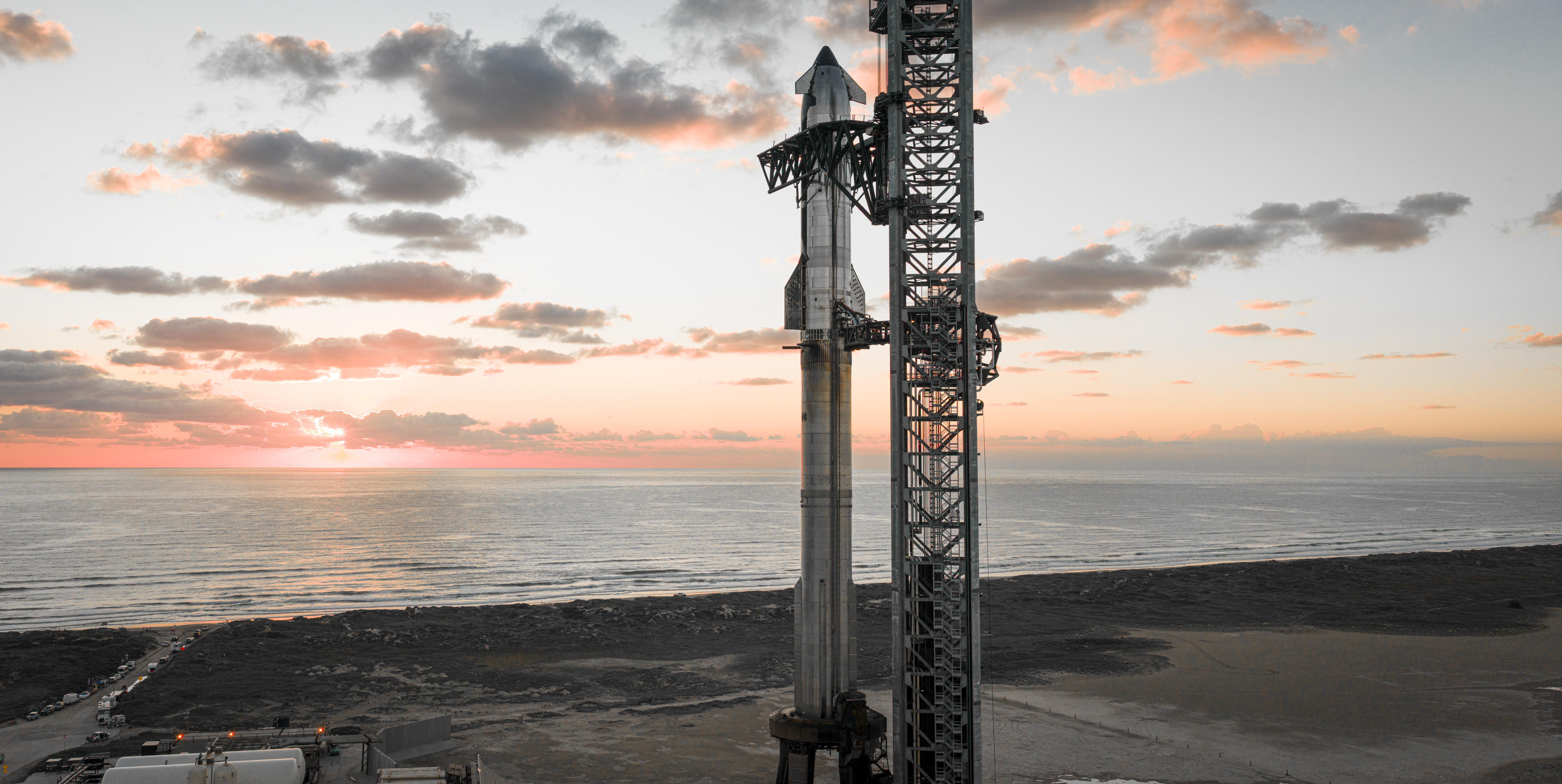 Full Starship stack on the launch pad against a sunset sky in Boca Chica, Texas.