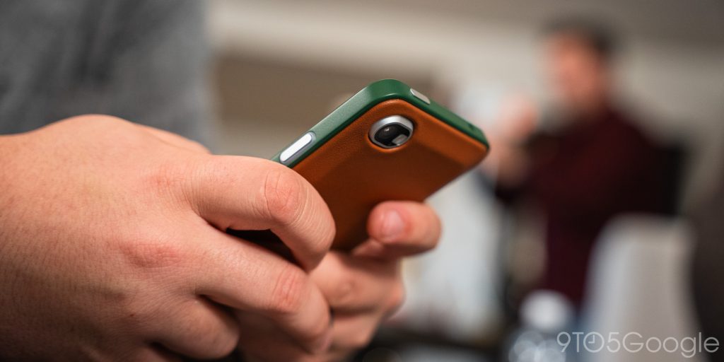 A person holding the Clicks Communicator, showing the screen interface and the physical keyboard layout.