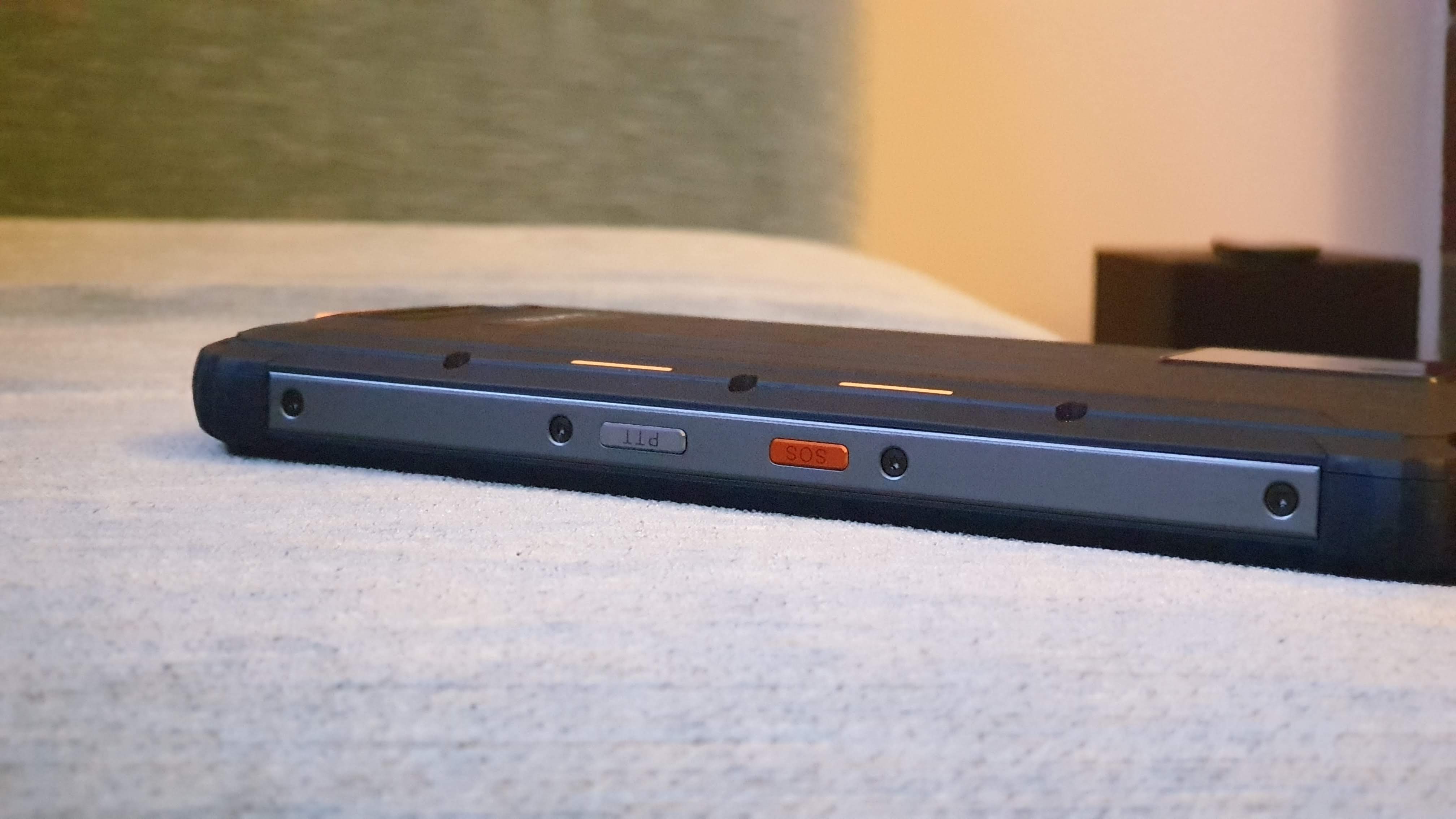 Detail of red and orange physical buttons on the side of a rugged phone chassis.