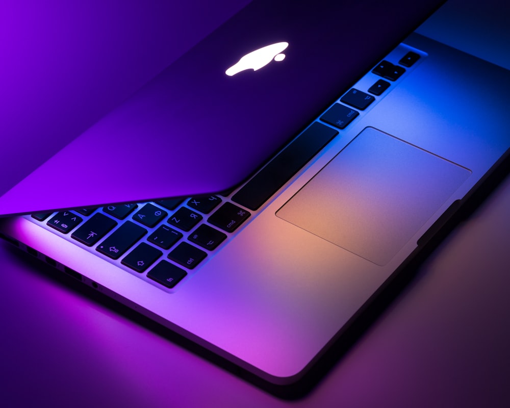 A MacBook Pro with a vibrant high-resolution screen set against a dark, minimalist background.