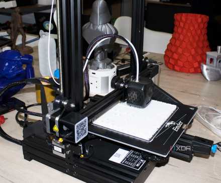A 3D printer actively printing a white plastic component on a build plate.