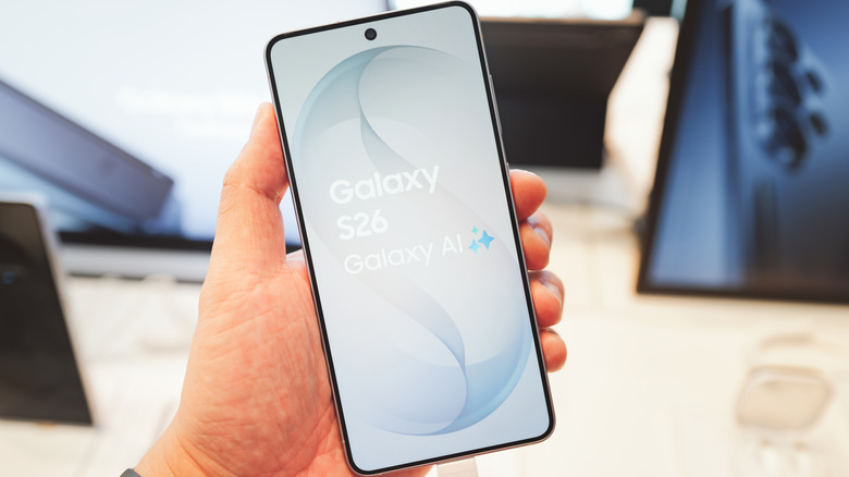 A hand holding the Samsung Galaxy S26 displaying the Galaxy AI logo on the screen.