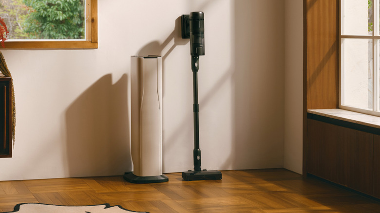 A Roborock H60 Hub Ultra stick vacuum standing next to its white and black auto-empty dock.