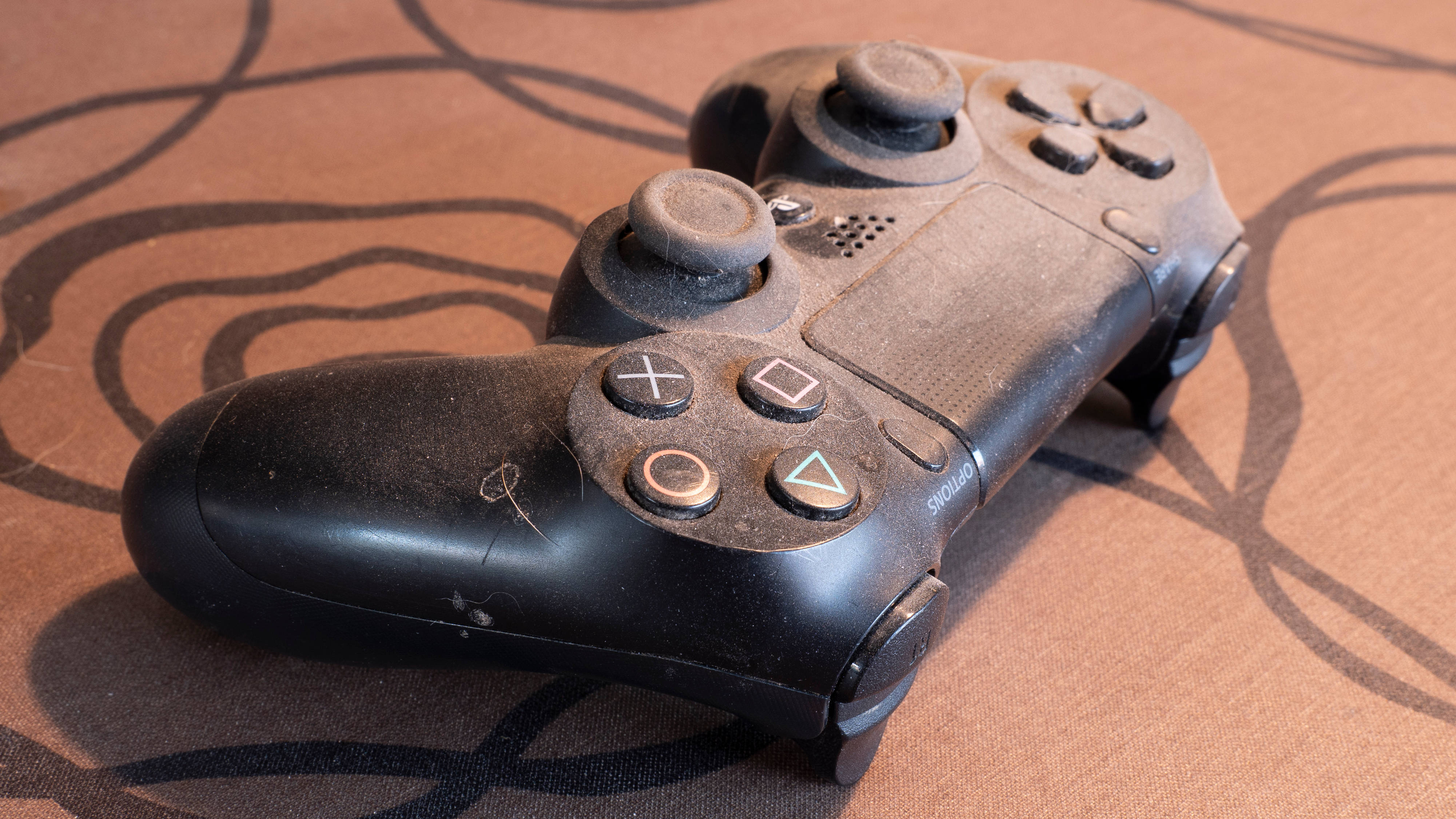 Close-up of a PlayStation 4 controller covered in a thick layer of dust.
