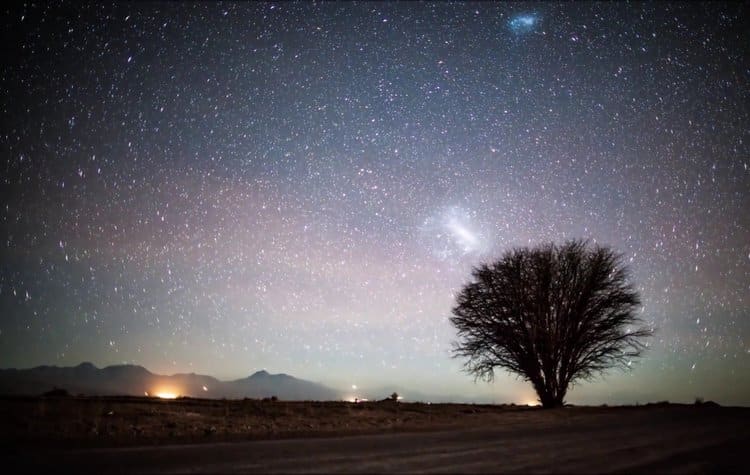 A group of tourists looking up at a dense field of stars in a dark sky park.