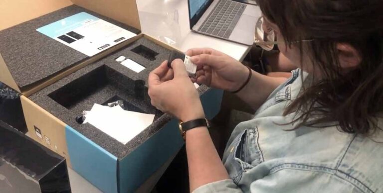 Two people examining and testing various home security camera components on a table.