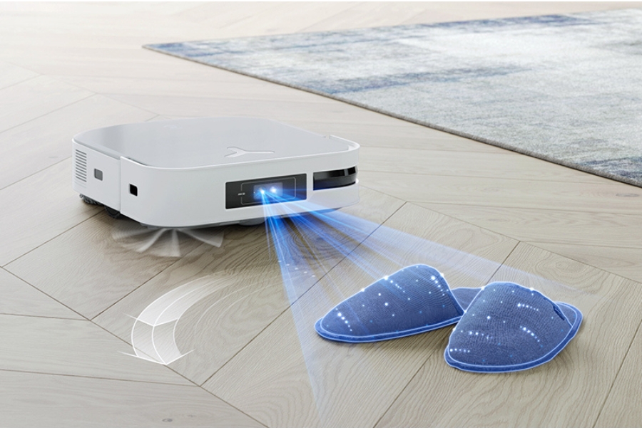 A robot vacuum stopping in front of a pair of slippers, showing its object recognition capabilities.