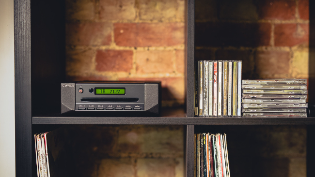 A Cyrus CDi player positioned next to several stacked CD jewel cases.