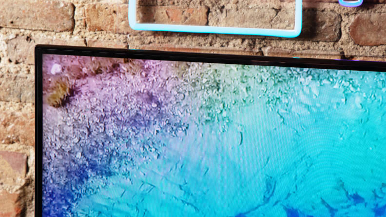 A side-profile detail of the Hisense U8N display showing the slim bezel and vibrant screen in front of a brick wall.