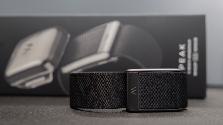 A Whoop fitness tracking band positioned creatively in front of its original box.