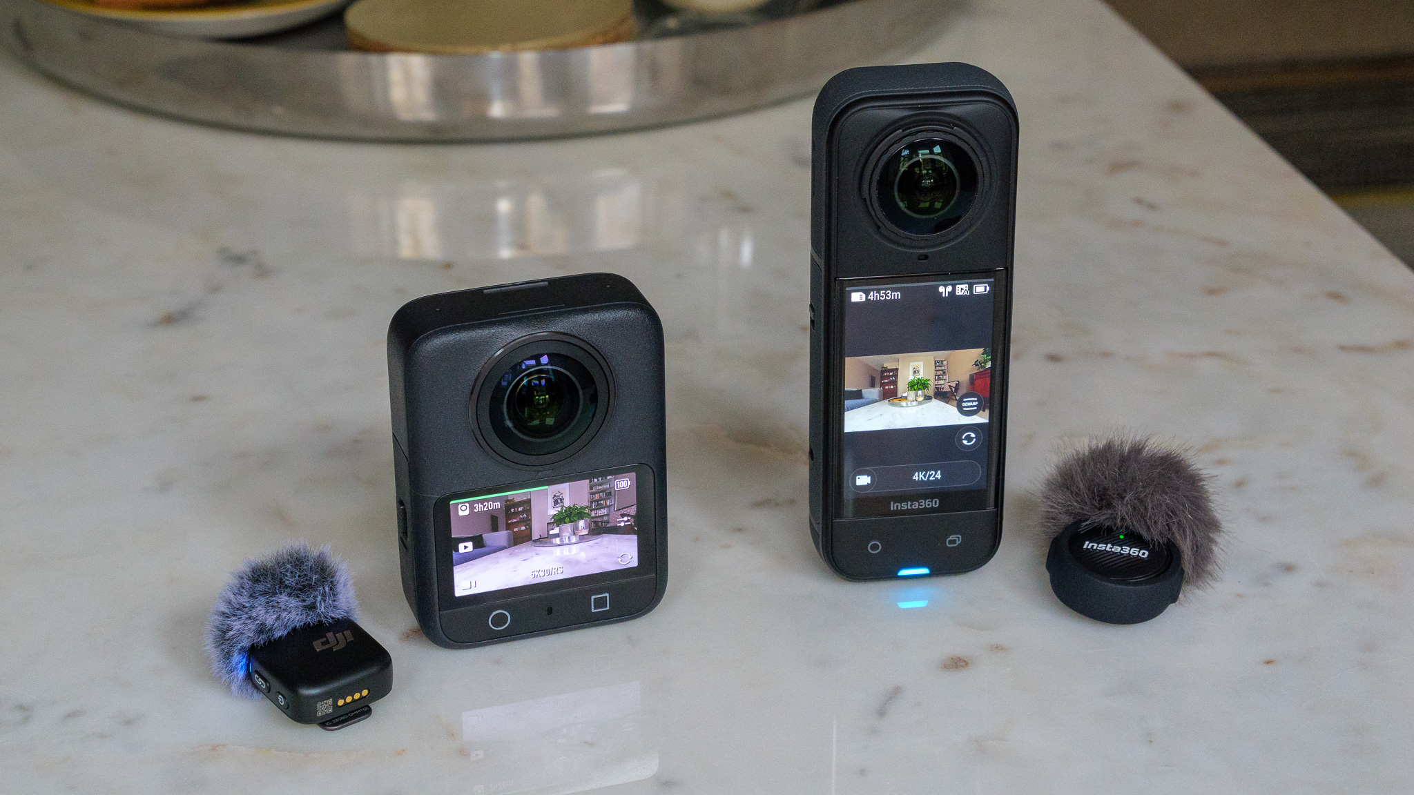 DJI Osmo 360 and Insta360 X5 on a table accompanied by wireless microphone systems.