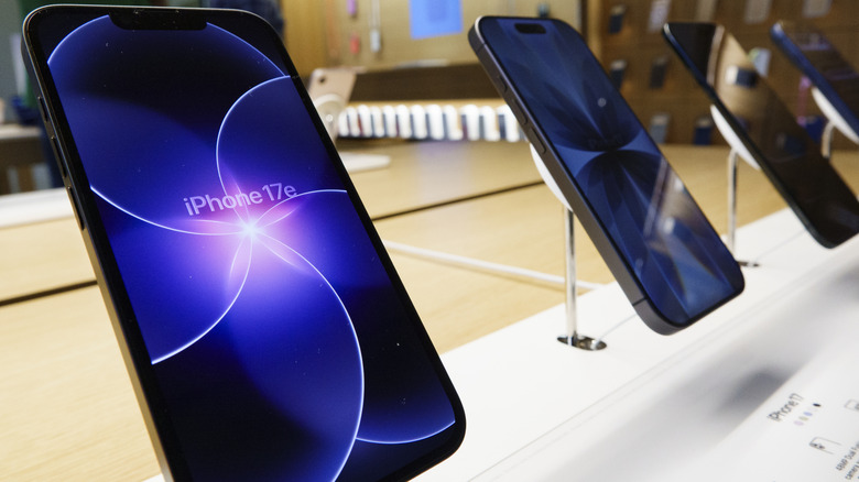 The iPhone 17e on a wooden display table inside an Apple Store.