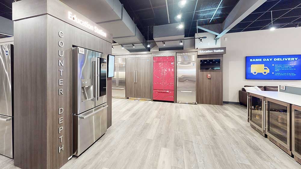 Comparison display of different refrigerator depths and types at an appliance showroom.