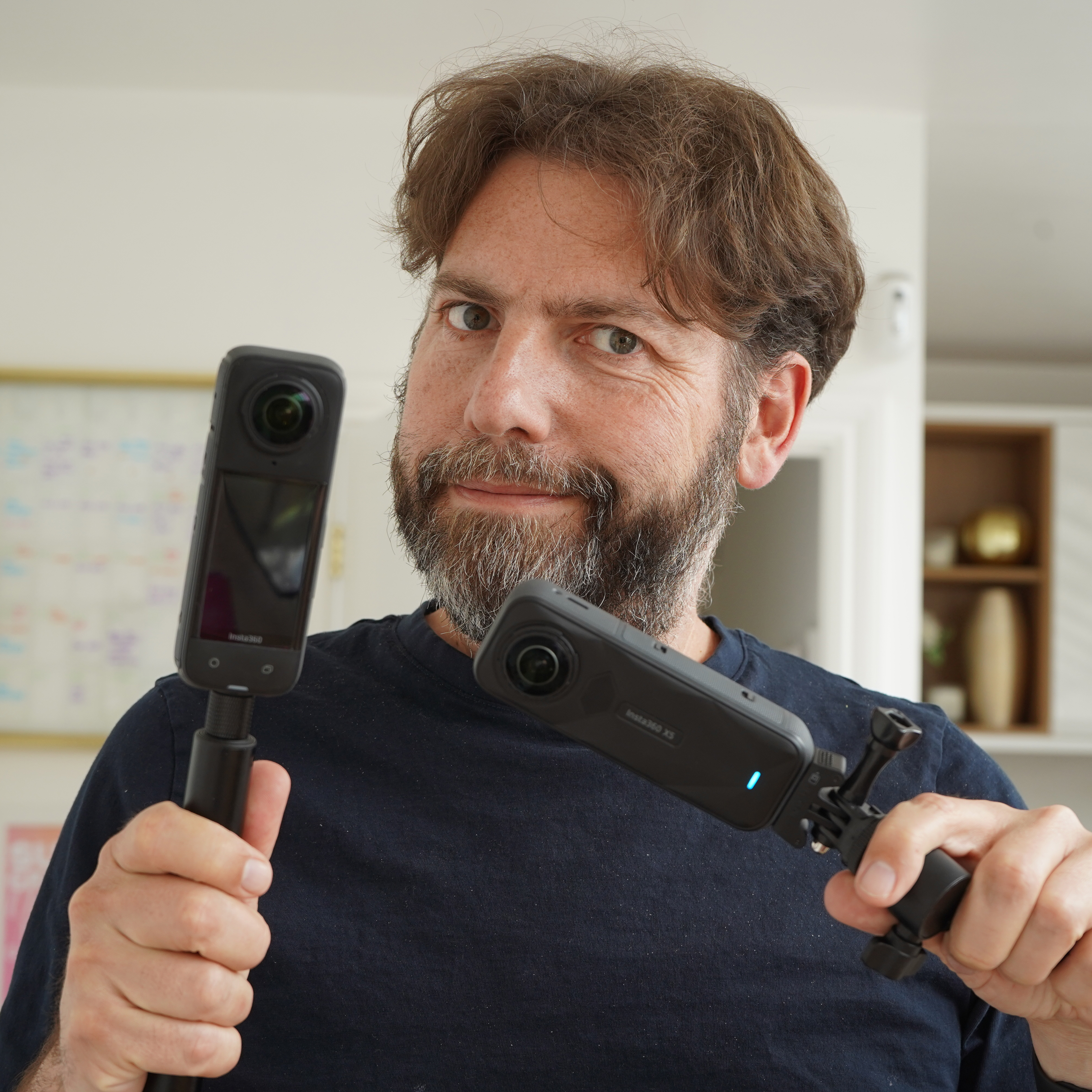 A person holding the Insta360 X5 and its predecessor the X4 for comparison.