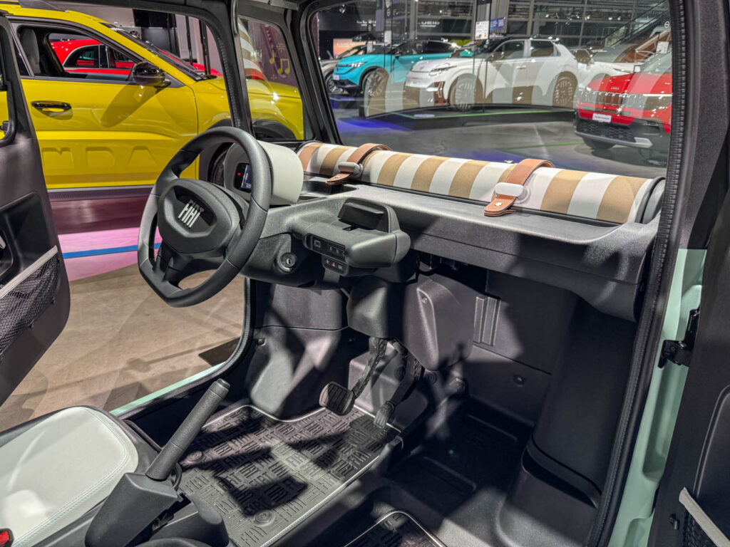 Interior dashboard and steering wheel of the Fiat Topolino showing a minimalist digital display
