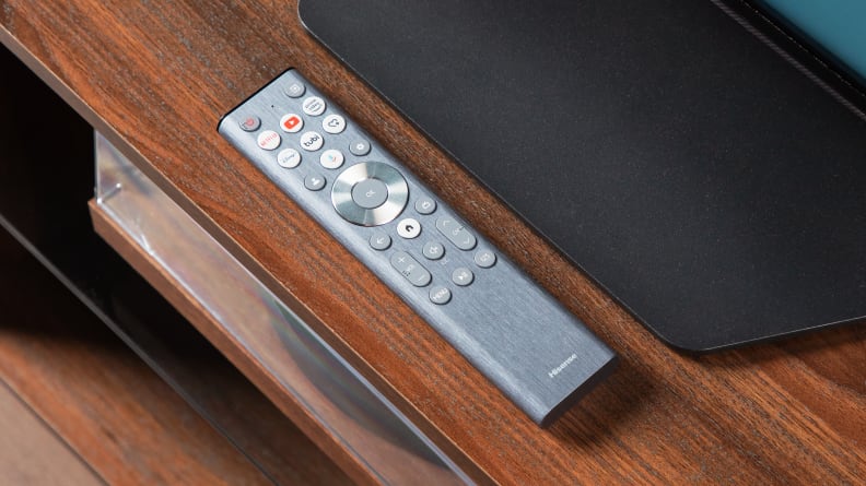 Close-up of the Hisense U8N backlit silver remote control resting on a wooden surface.