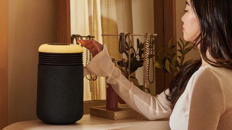 A person placing their hand on a Blueair Mini Restful air purifier to show its compact size.