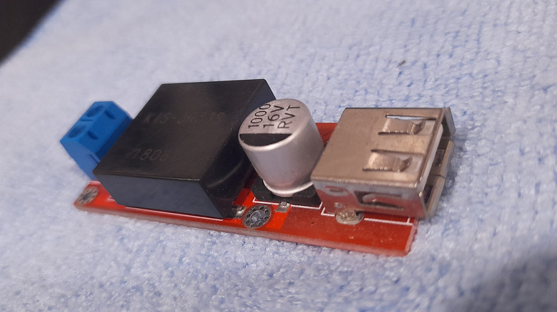 Close-up of a small DC-DC converter chip on a green PCB