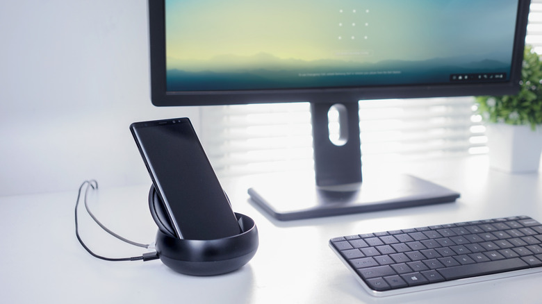 A Samsung Galaxy phone connected to a monitor showing the Samsung DeX desktop interface.