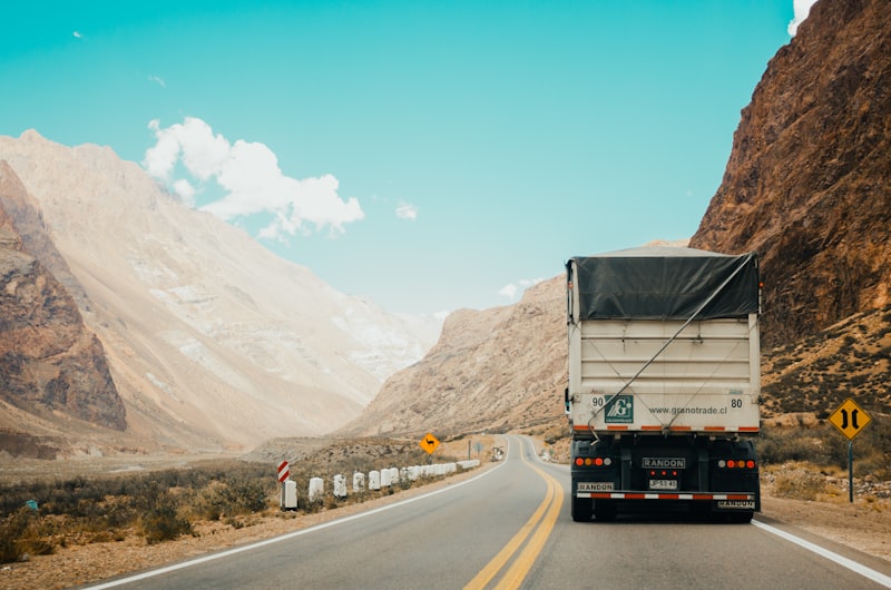 A delivery truck driving on an open highway during sunset.