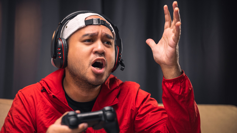 An frustrated gamer holding a gaming controller while playing.