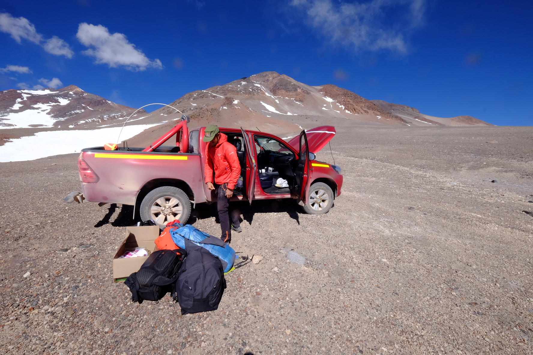 A white expedition vehicle stalled in a vast, desolate desert landscape.