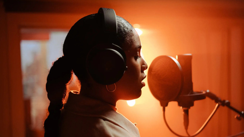 A professional singer using Beyerdynamic DT 700 Pro X headphones in a recording studio.
