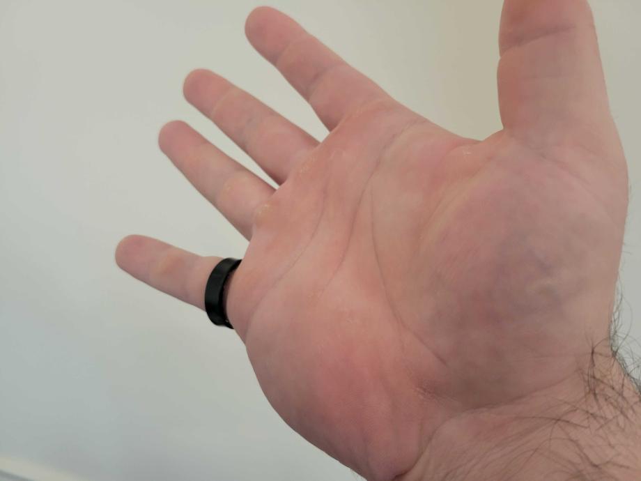 A person wearing a minimalist silver Samsung Galaxy Ring on their index finger.