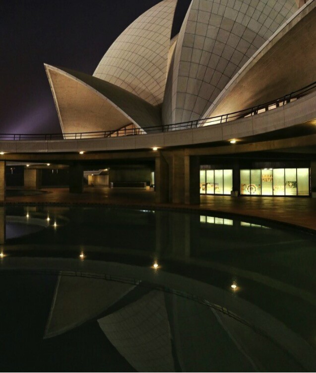 A wireless remote shutter release being held in front of a camera mounted on a tripod.
