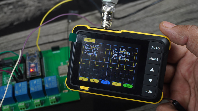An engineer using a digital oscilloscope to analyze a circuit's waveform