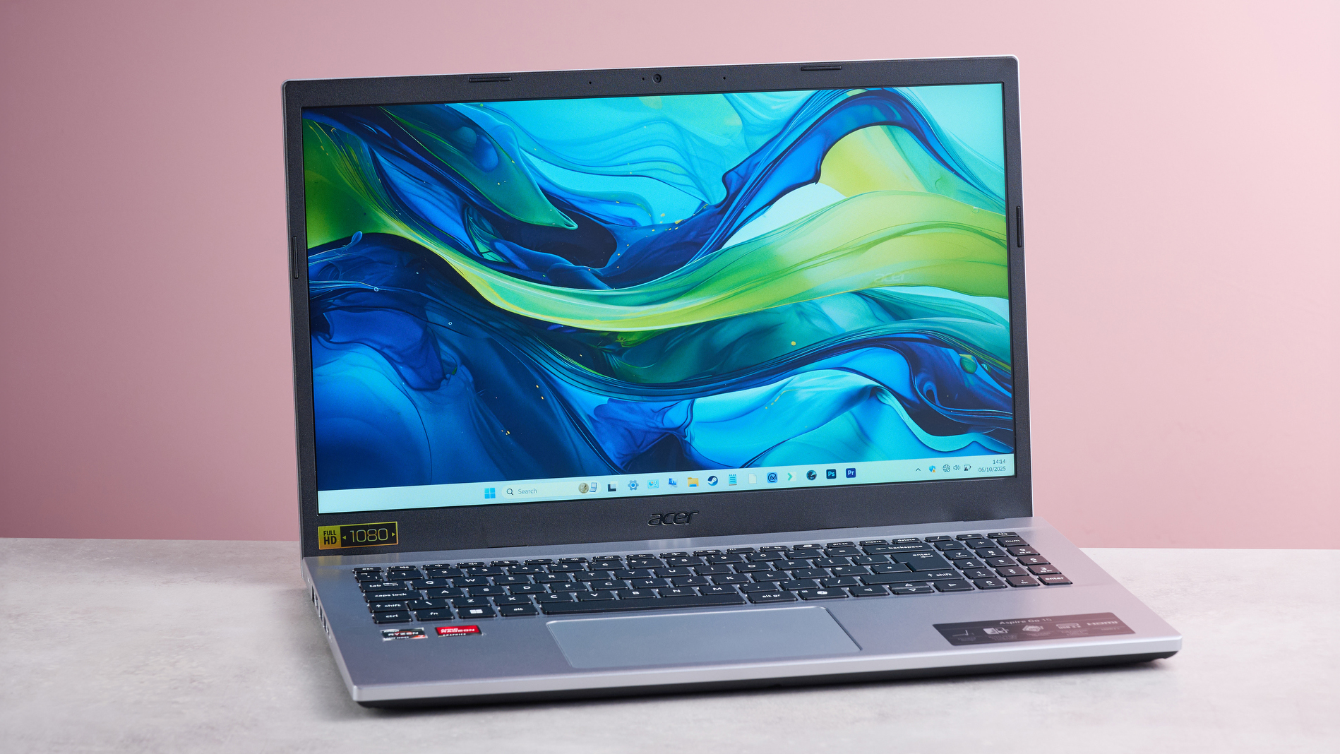 The Acer Aspire Go 15 laptop resting on a desk against a pink background.