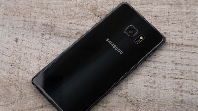 A black Samsung Galaxy Note 7 smartphone placed face down on a wooden surface.
