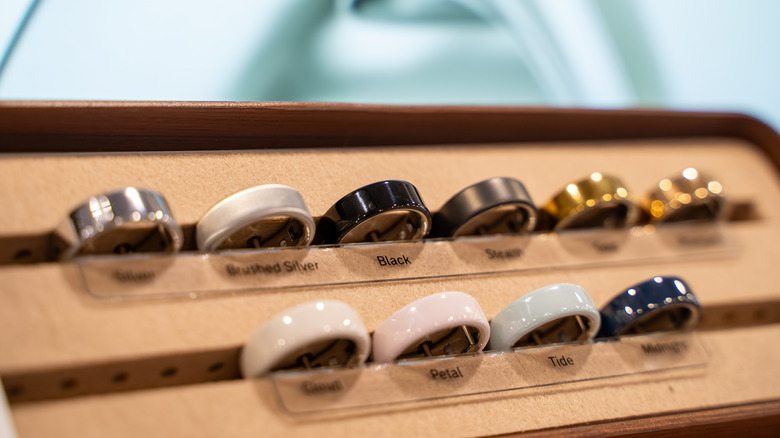 A row of various metallic smart rings displayed on specialized retail stands.