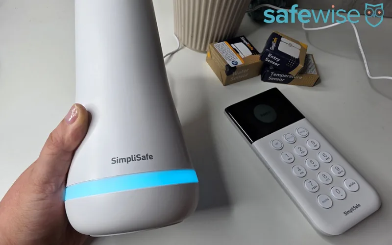 An expert setting up a white security base station on a wooden surface.