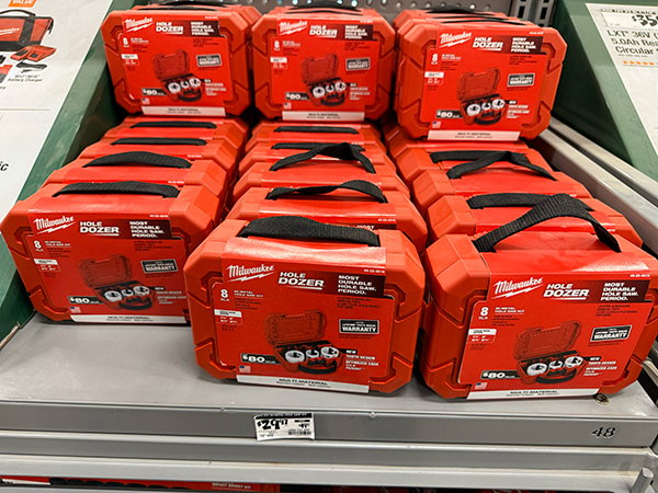 Milwaukee brand hole saw sets displayed on a retail shelf with holiday pricing.