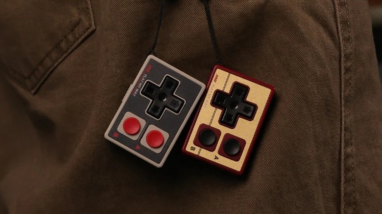 Two small bluetooth controllers with a retro NES-style design in red and gold finishes.