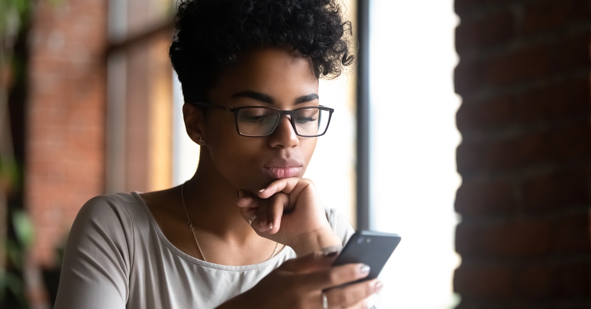 A woman holding a smartphone while browsing the internet.