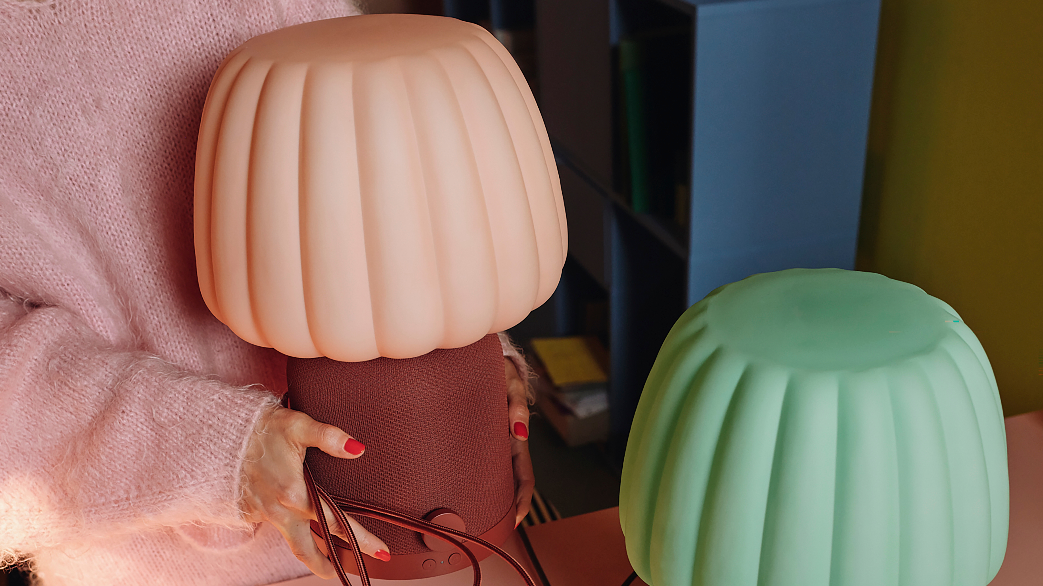 IKEA KULGLASS lamp speakers in soft green and red-brown shades on a desk.
