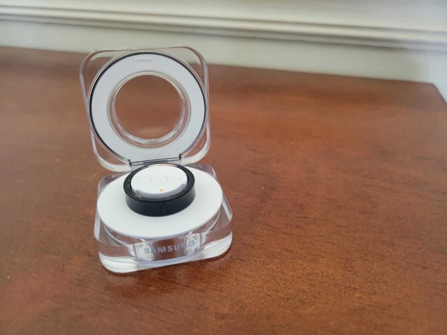 The Samsung Galaxy Ring sitting inside its transparent, illuminated portable charging case.