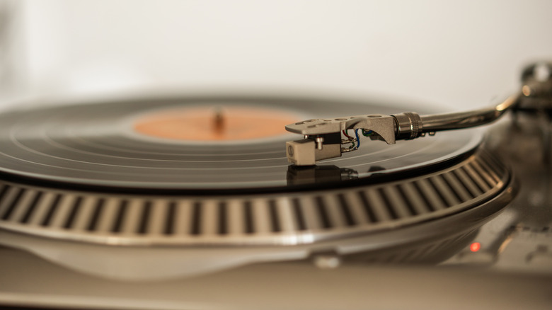 A vintage record player with a black vinyl record spinning under an analog needle.