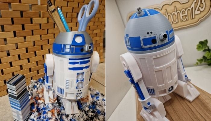 A multicolor 3D printed R2-D2 droid being used as a pen holder on a desk.
