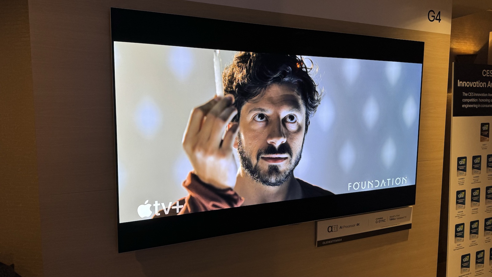 An LG G4 OLED TV showing the Apple TV interface with high-quality cinematic content.