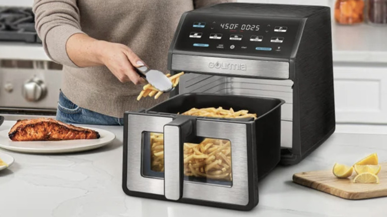 A woman using the Gourmia 8-Quart Digital Air Fryer to make golden french fries.