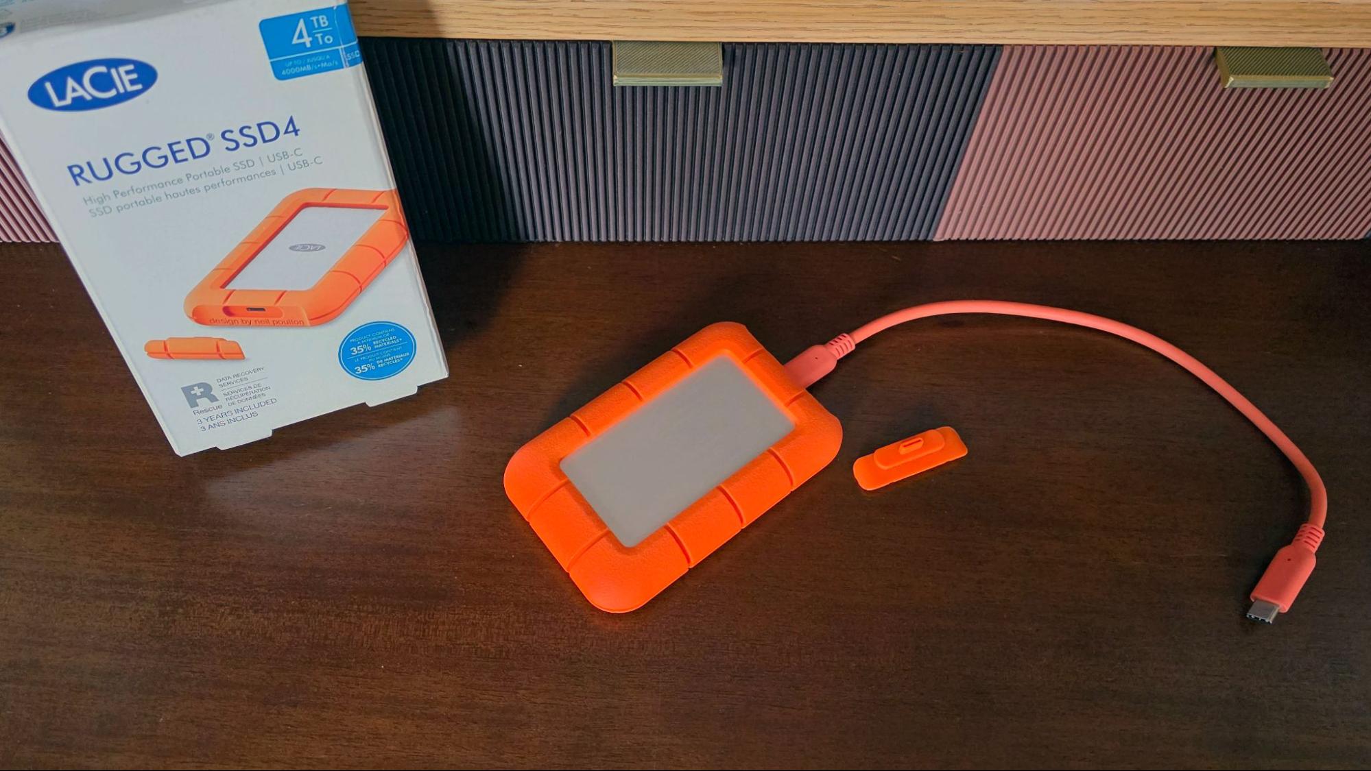 An orange LaCie Rugged SSD with a thick protective rubber bumper.
